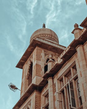 A close-up of historic architectural details featuring a dome in India, clear sky background.