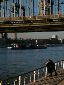 A couple enjoys the view of the Rhine River under a bridge in Cologne, Germany.