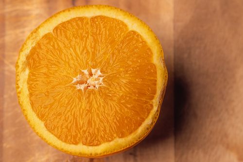 Free Vibrant orange half on a wooden background, showcasing juicy texture and bright color. Stock Photo
