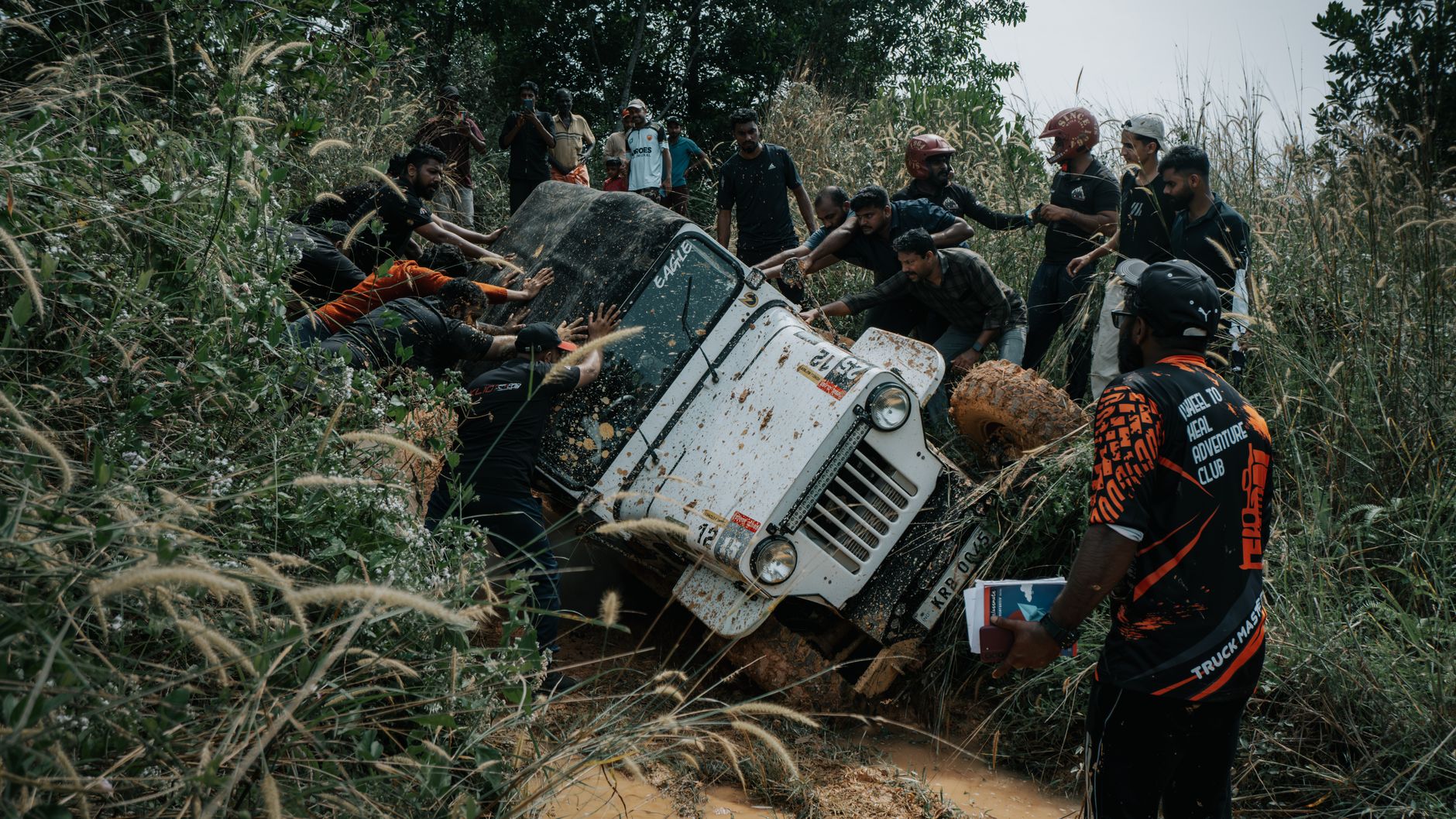Group of people recovering a stuck off-road vehicle buried in mud on a backcountry trail