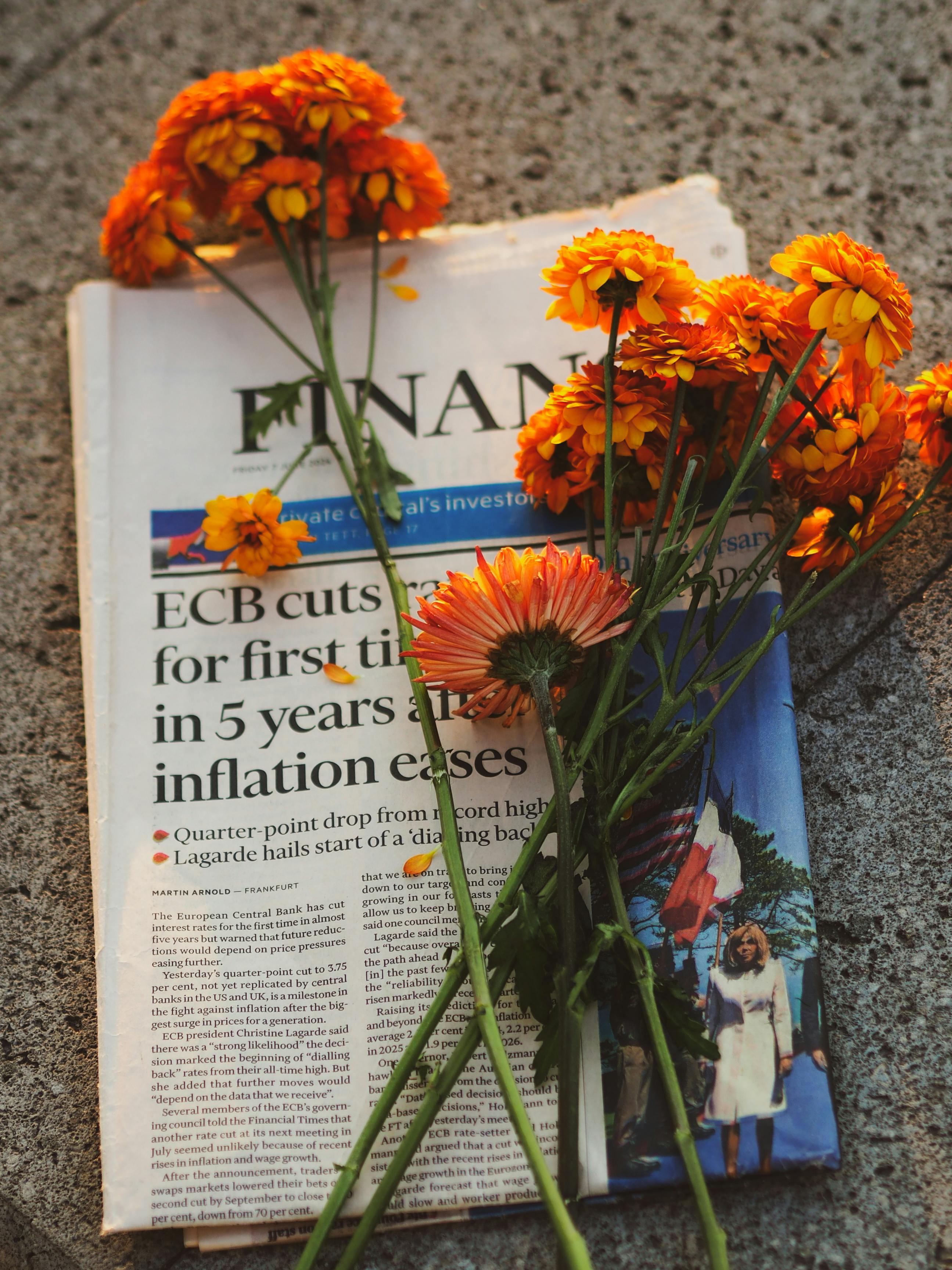 orange marigolds on newspaper with financial headlines