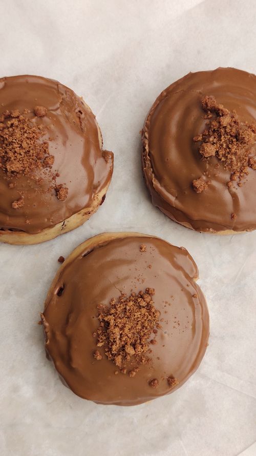 Free Delicious chocolate glazed doughnuts with crumbled topping on parchment paper. Stock Photo