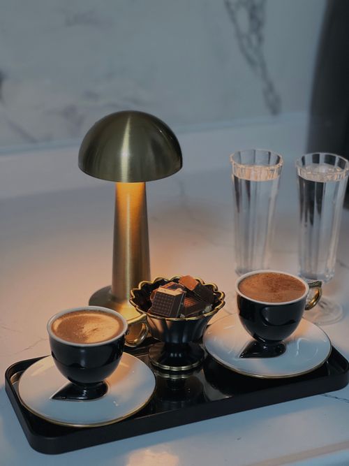 Free A chic setup of two espresso cups with chocolates and a modern lamp, perfect for a cozy moment. Stock Photo