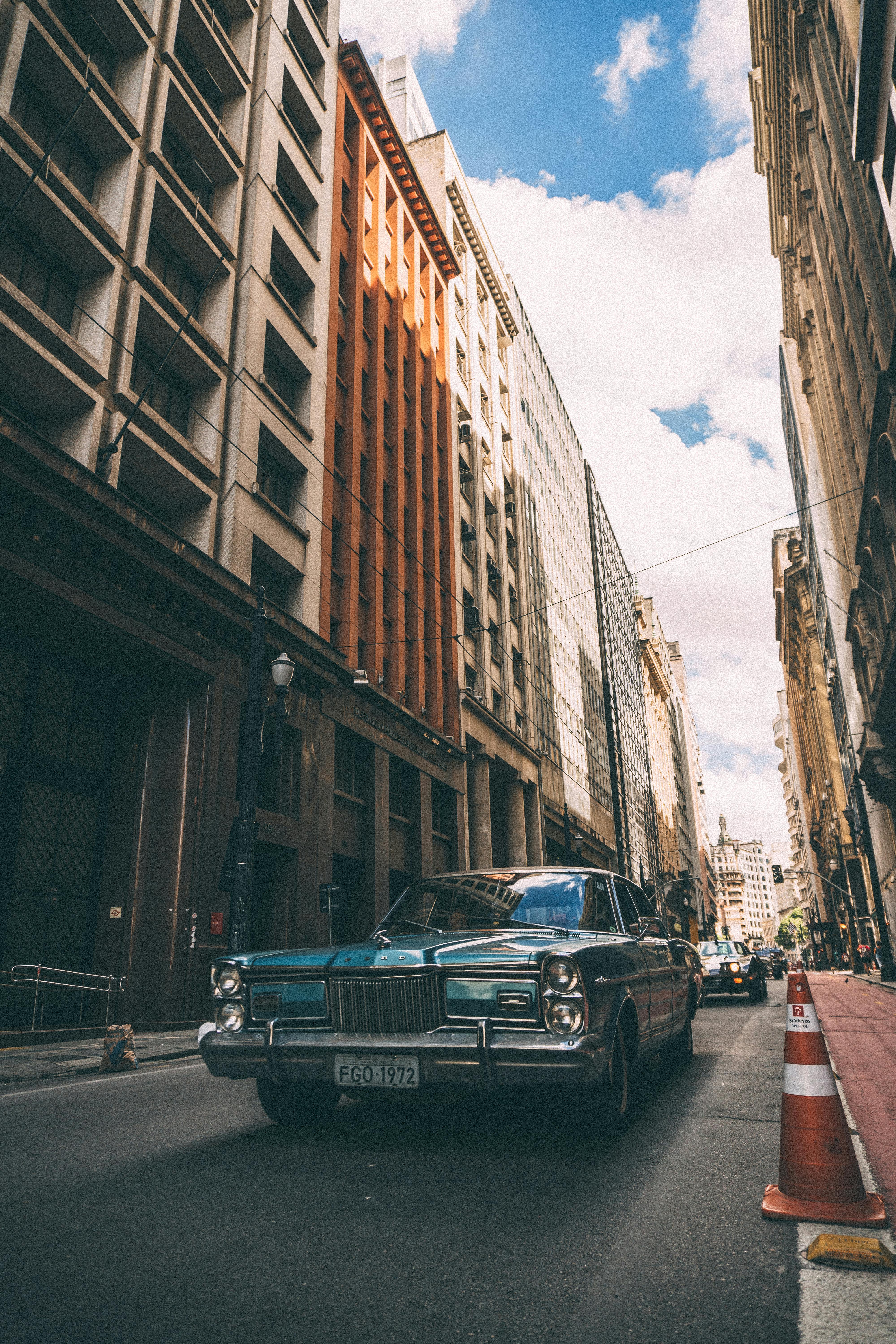 一辆经典古董车行驶在繁忙的城市街道上，头顶是晴朗的蓝天