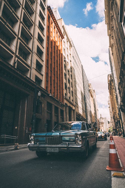 Teal Car on Roadway Beside City Buildings