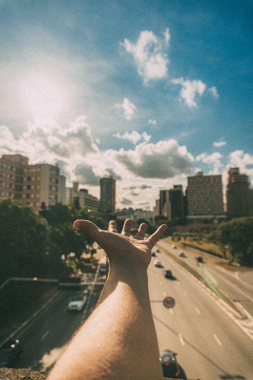 Person's Hand Near High-rise Buildings