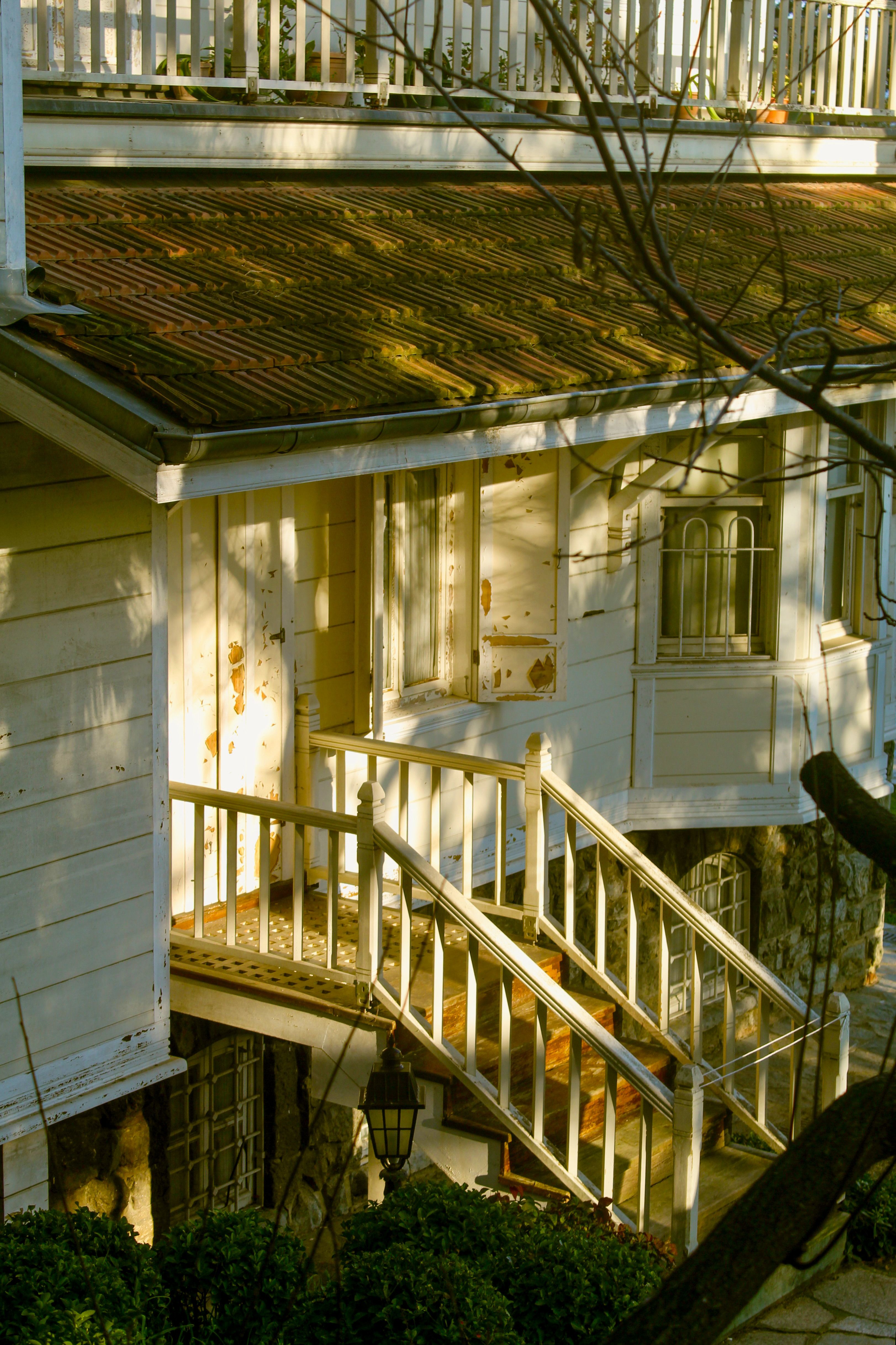 Charming rustic wooden house exterior with sunlit weathered details and railing.
