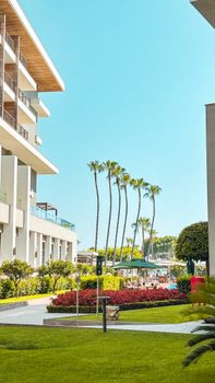 View of a luxury hotel's exterior in Antalya with palm trees and garden.