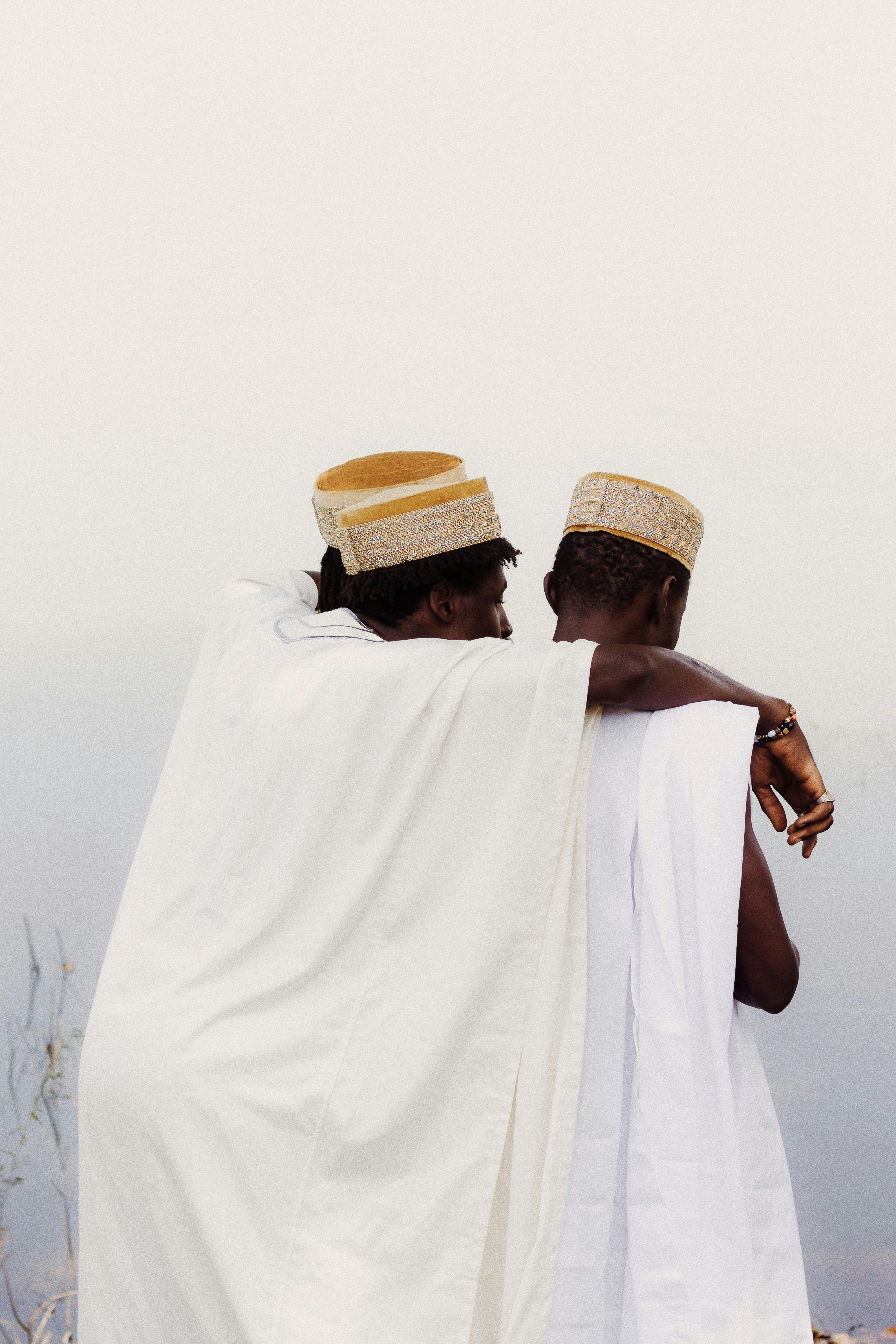 Two men in traditional Nigerian attire embracing outdoors, symbolizing friendship and culture.