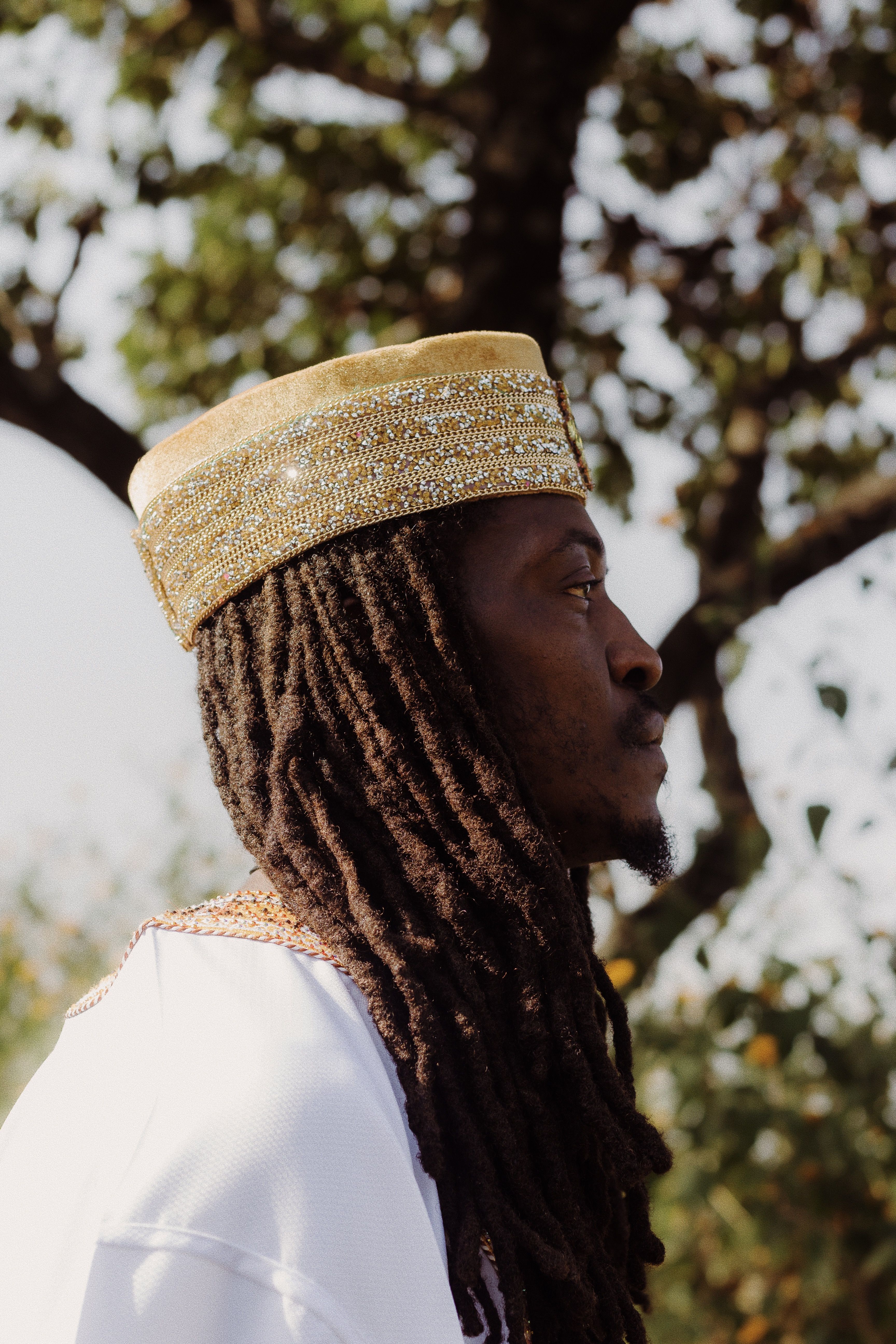 A man in traditional Nigerian attire stands outdoors, showcasing cultural heritage.