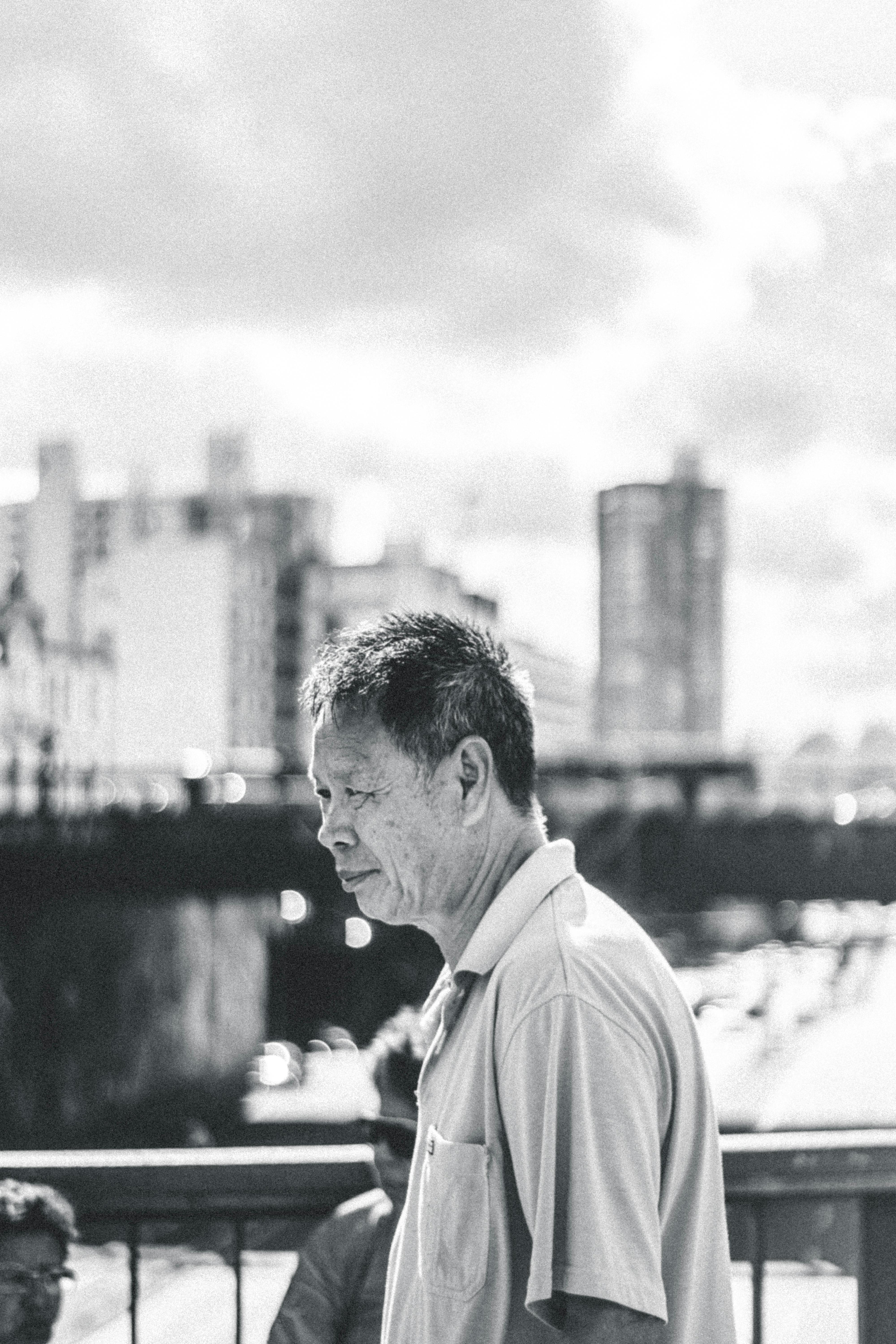 黑白肖像描绘了一位走在桥上、背景是城市天际线的深思熟虑的男人