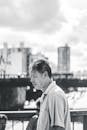 黑白肖像描绘了一位走在桥上、背景是城市天际线的深思熟虑的男人