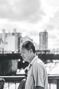 黑白肖像描绘了一位走在桥上、背景是城市天际线的深思熟虑的男人