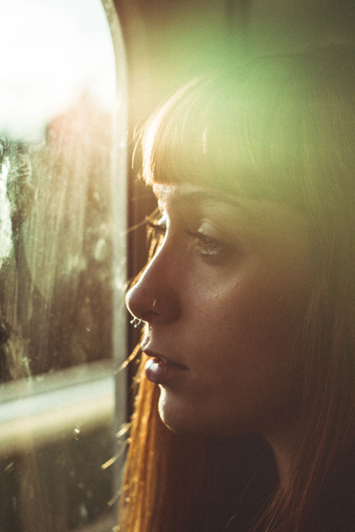 A woman looking out a window in warm sunlight