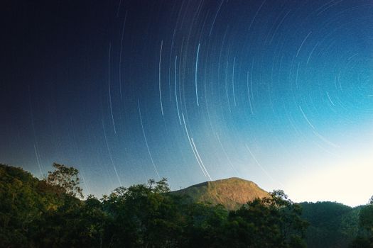 Stunning long exposure star trails captured over a scenic mountain landscape at night.