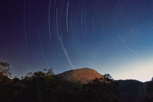Free Long exposure star trails over a serene mountain landscape at night, capturing the beauty of nature. Stock Photo