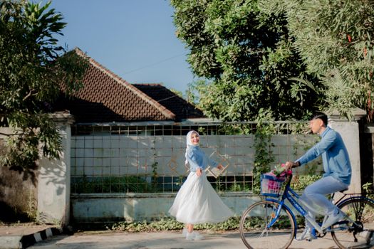 A joyful couple enjoying an outdoor pre-wedding photoshoot in Indonesia, with vibrant surroundings. - Fotografer Sidoarjo