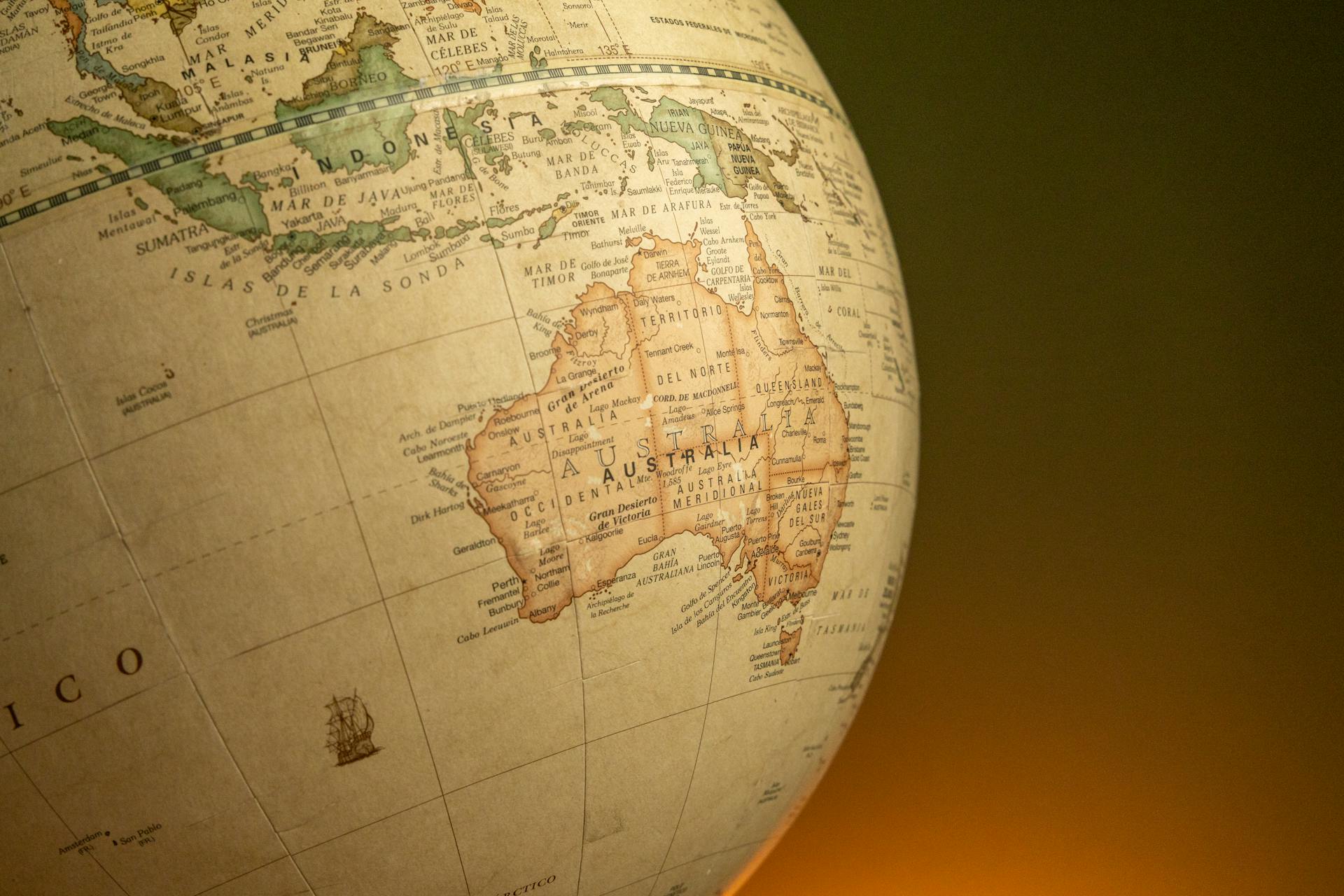 A close-up of a vintage map globe showcasing Australia and Indonesia against a warm background.