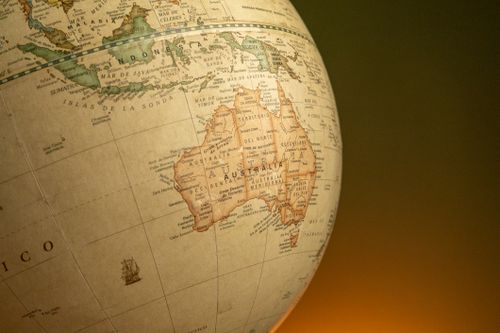 Free A close-up of a vintage map globe showcasing Australia and Indonesia against a warm background. Stock Photo