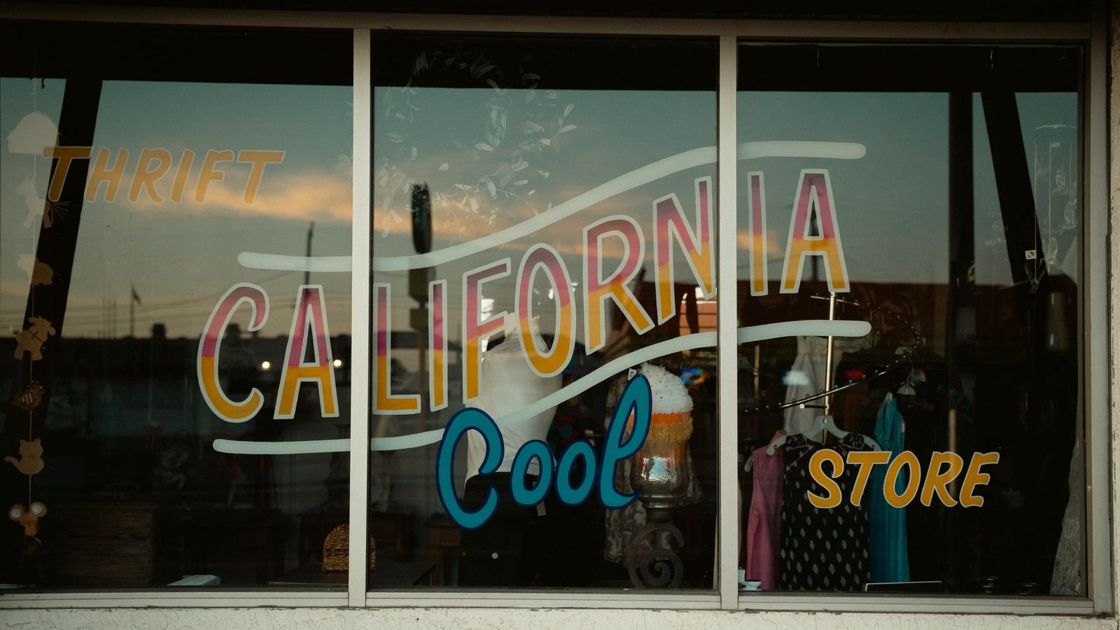 Vintage shop window with retro California thrift store signage and colorful display.