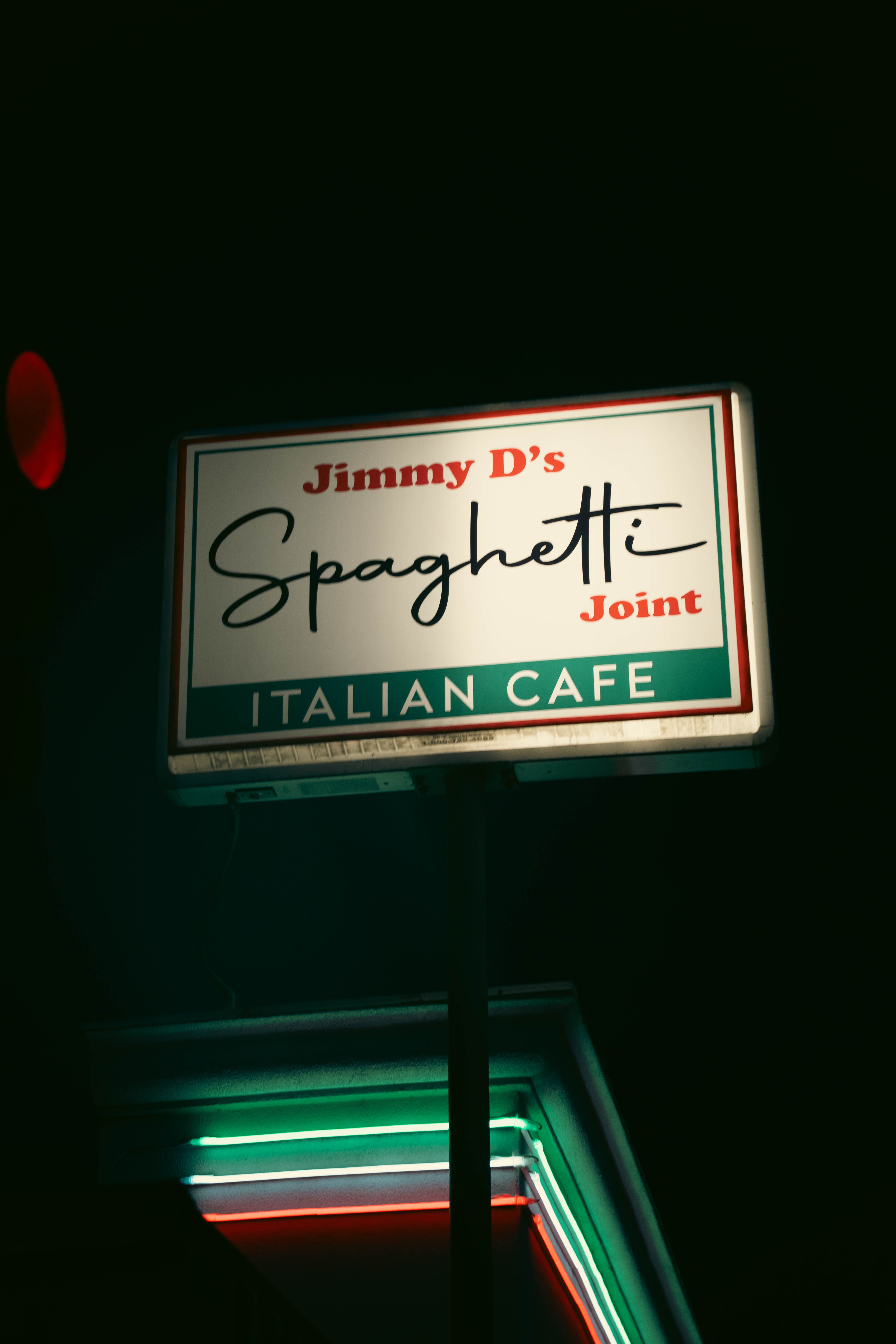 Illuminated sign of Jimmy D's Spaghetti Joint, an Italian cafe, captured at night.