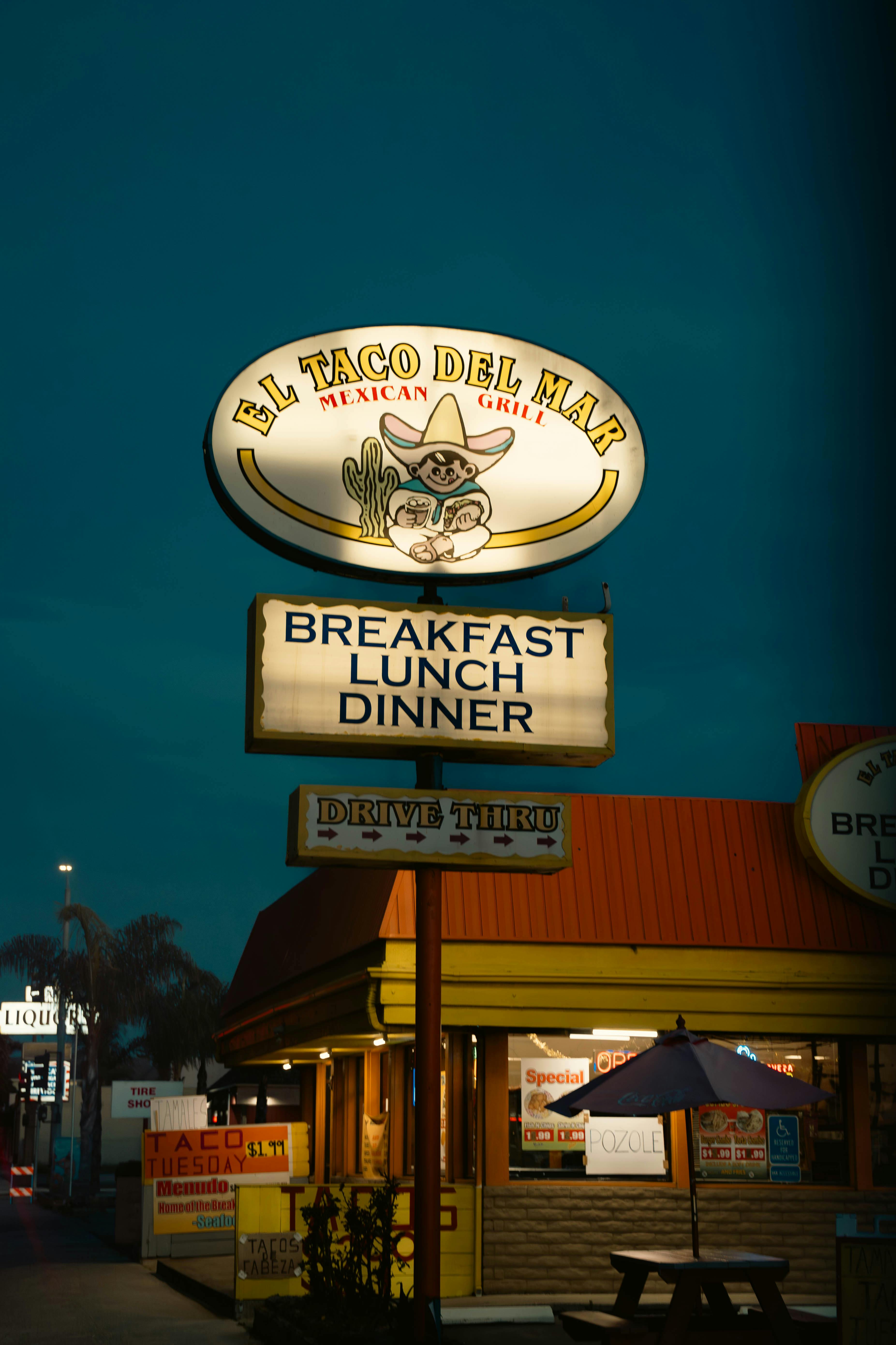 Nighttime view of a Mexican restaurant sign offering breakfast, lunch, and dinner.