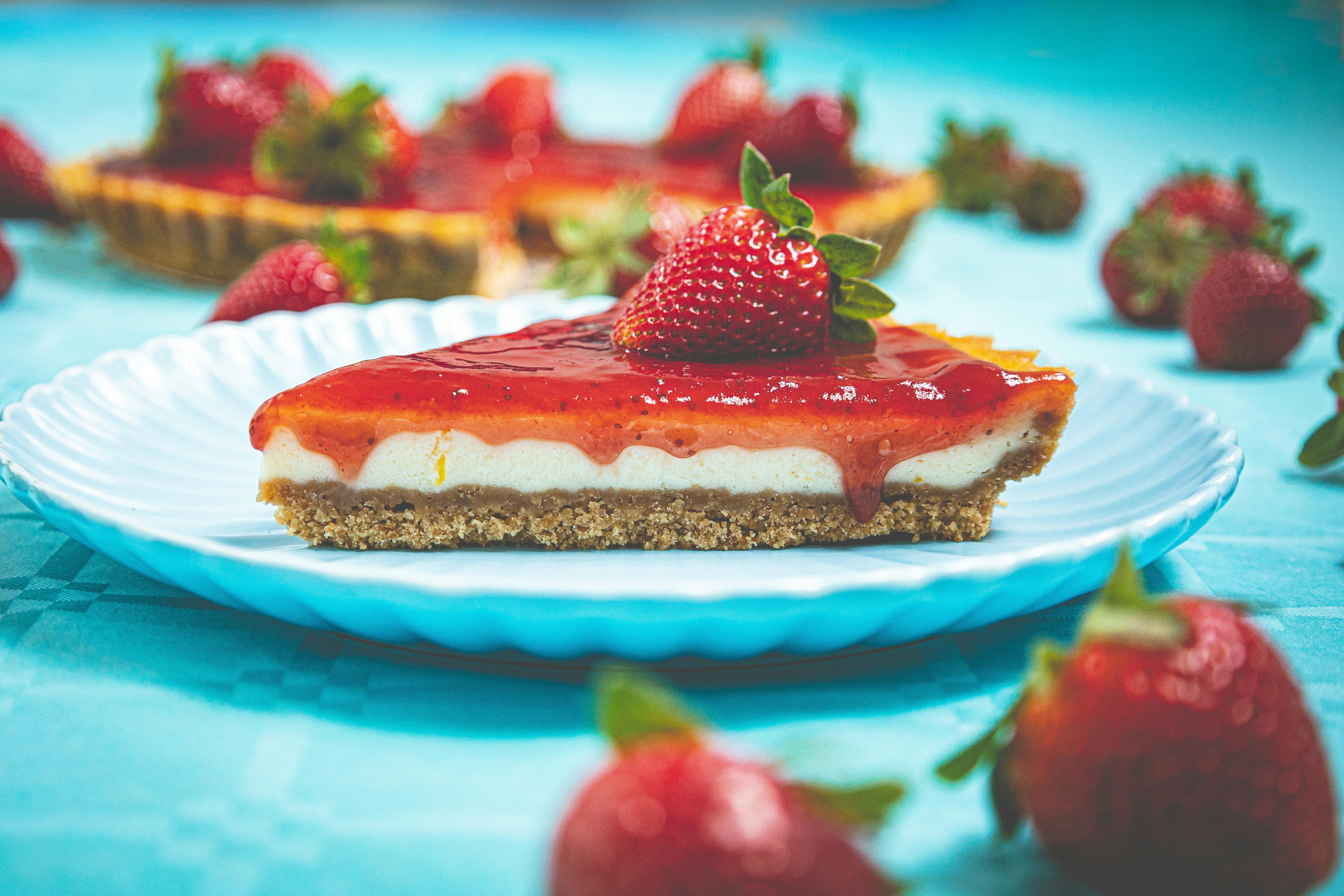A tempting slice of strawberry cheesecake garnished with fresh strawberries on a blue plate.