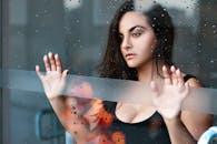 在巴西桑托斯，一位深思熟虑的女人在雨天站在玻璃窗后的肖像