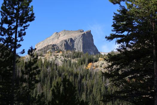 Scenic view of a towering mountain surrounded by lush forest in Rocky Mountain National Park, Colorado.