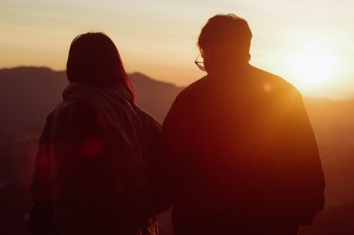 Free Silhouetted couple enjoys a warm sunset in a serene outdoor setting, creating a romantic atmosphere. Stock Photo