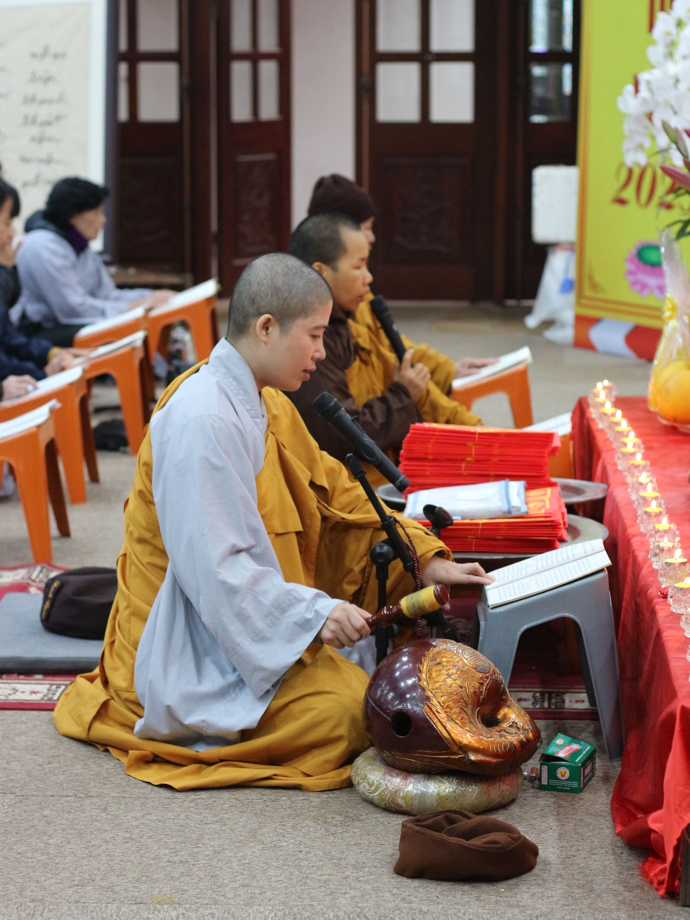 Buddhist monks engaged in meditation and prayer during a ceremonial gathering indoors.