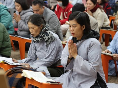 People gathered in meditation, wearing spiritual robes, focusing deeply in tranquil setting.