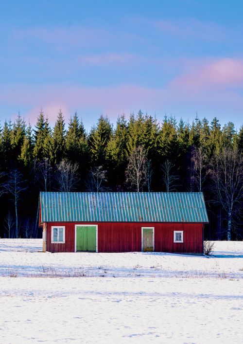 Free A charming red barn stands amid snowy fields in Uddeholm, Sweden. Stock Photo