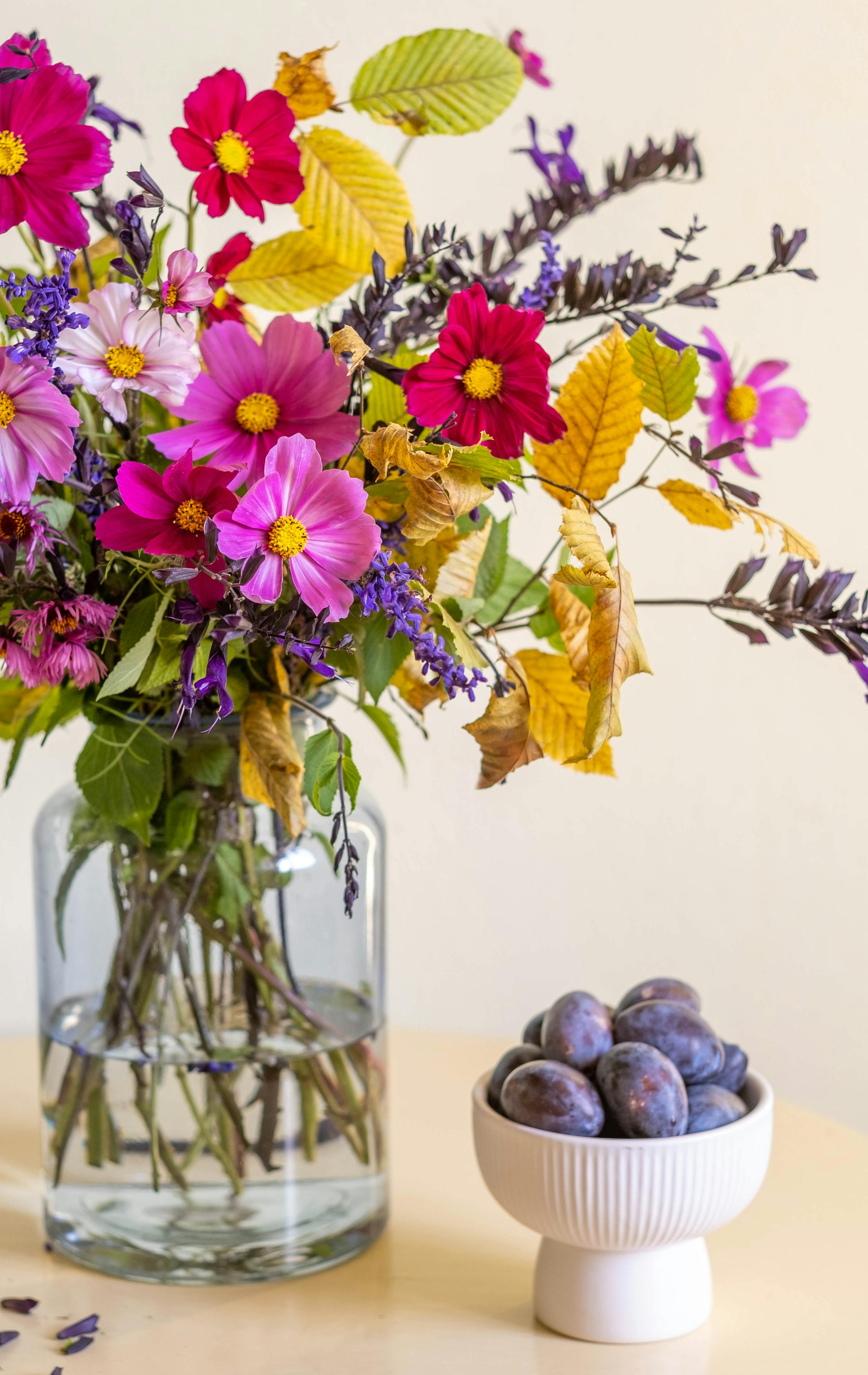 [ColoSach]-a-colorful-bouquet-of-autumn-flowers-in-a-vase-beside-a-bowl-of-fresh-plums.