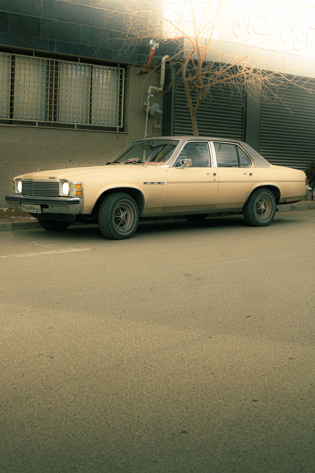 Older beige sedan parked on a quiet street