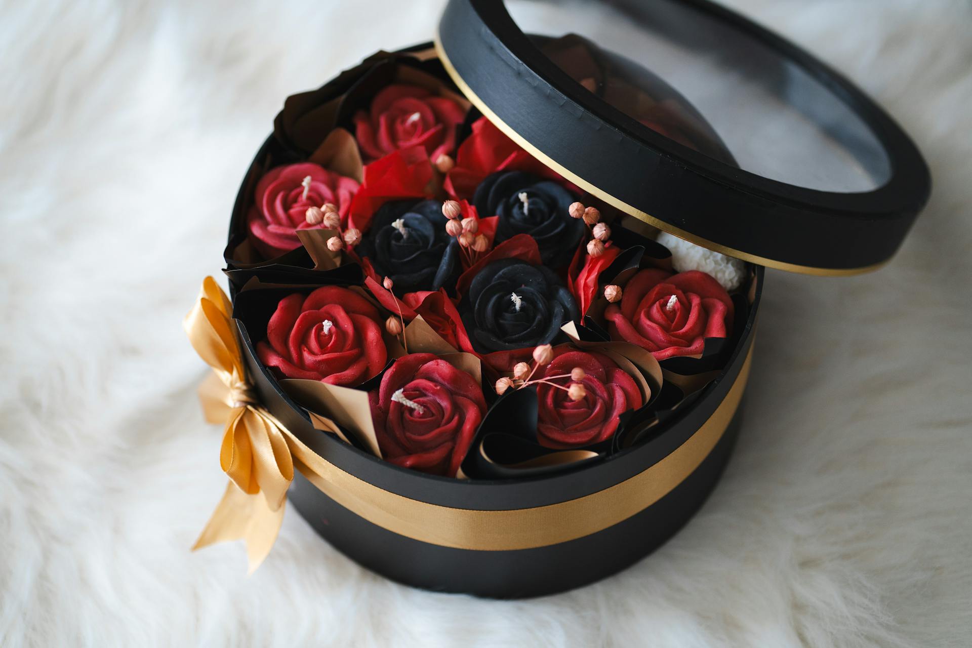 Luxurious round gift box featuring vibrant red and black artificial roses, perfect for special occasions.