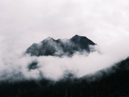 Free Serene misty mountain peaks rise through clouds in a tranquil landscape view. Stock Photo