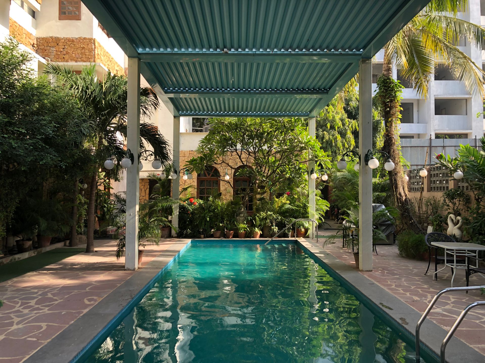 Serene tropical outdoor pool surrounded by lush greenery and shaded canopy.
