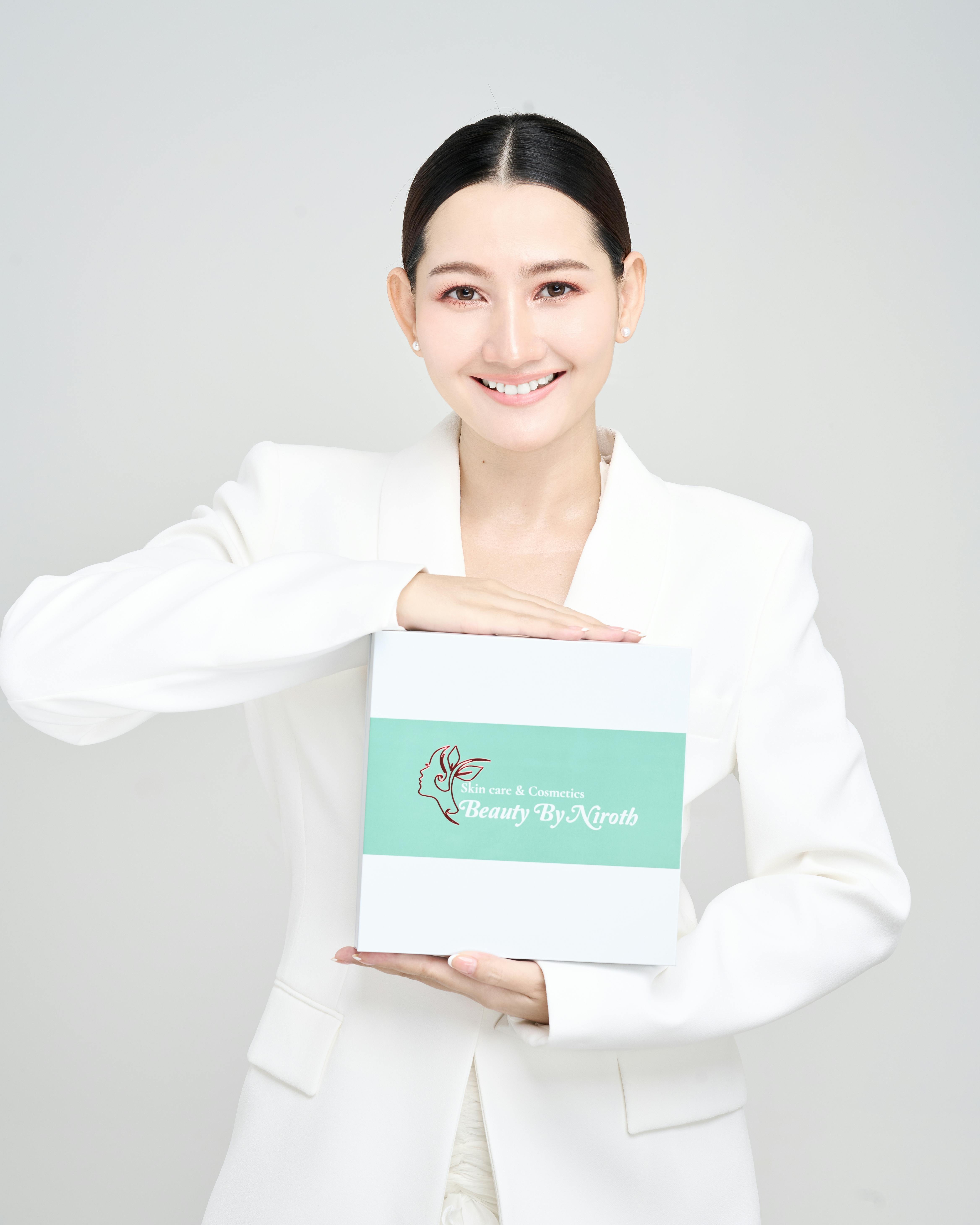 Gratis Mujer sonriente sosteniendo una caja de producto de belleza, ideal para promociones de cuidado de la piel. Foto de stock