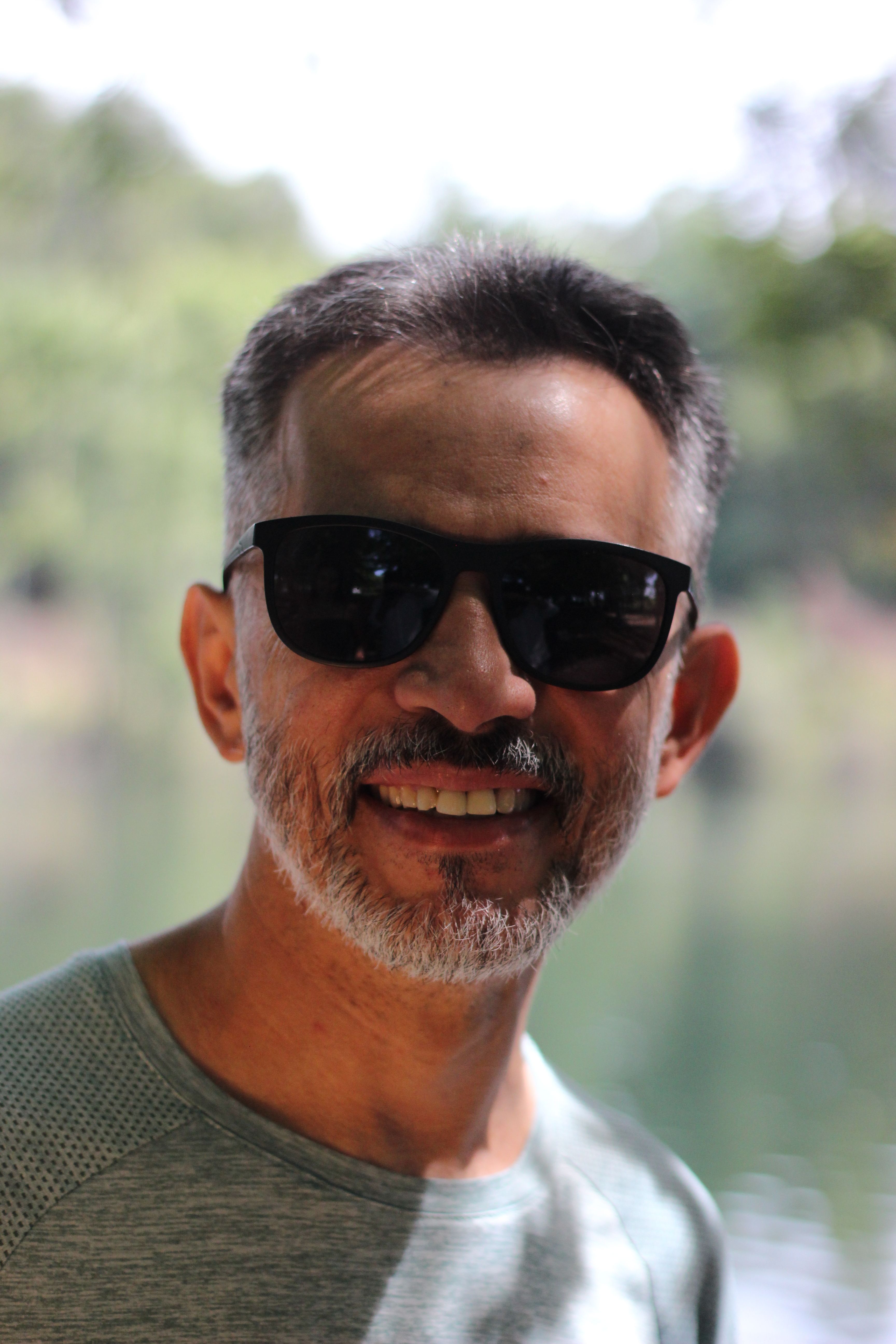A cheerful man with grey hair and sunglasses enjoying a sunny day outdoors in Braga, Portugal.