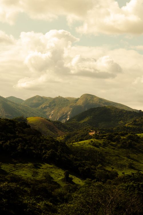 Free Serene view of lush green hills and mountains under a cloudy sky. Stock Photo
