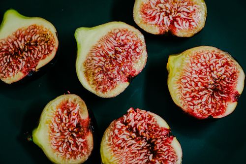 Gratis Un'immagine ravvicinata e dettagliata di fichi maturi tagliati a fette e disposti su uno sfondo scuro. Foto a disposizione