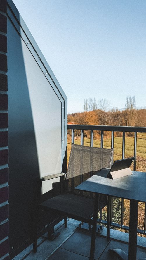 Free A serene balcony with a tablet on the table, overlooking a picturesque landscape in fall. Stock Photo
