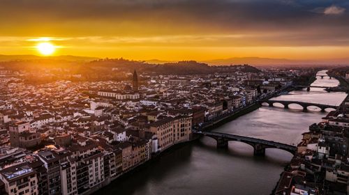 Free A breathtaking aerial view of Florence at sunset with the Arno River and iconic Ponte Vecchio. Stock Photo
