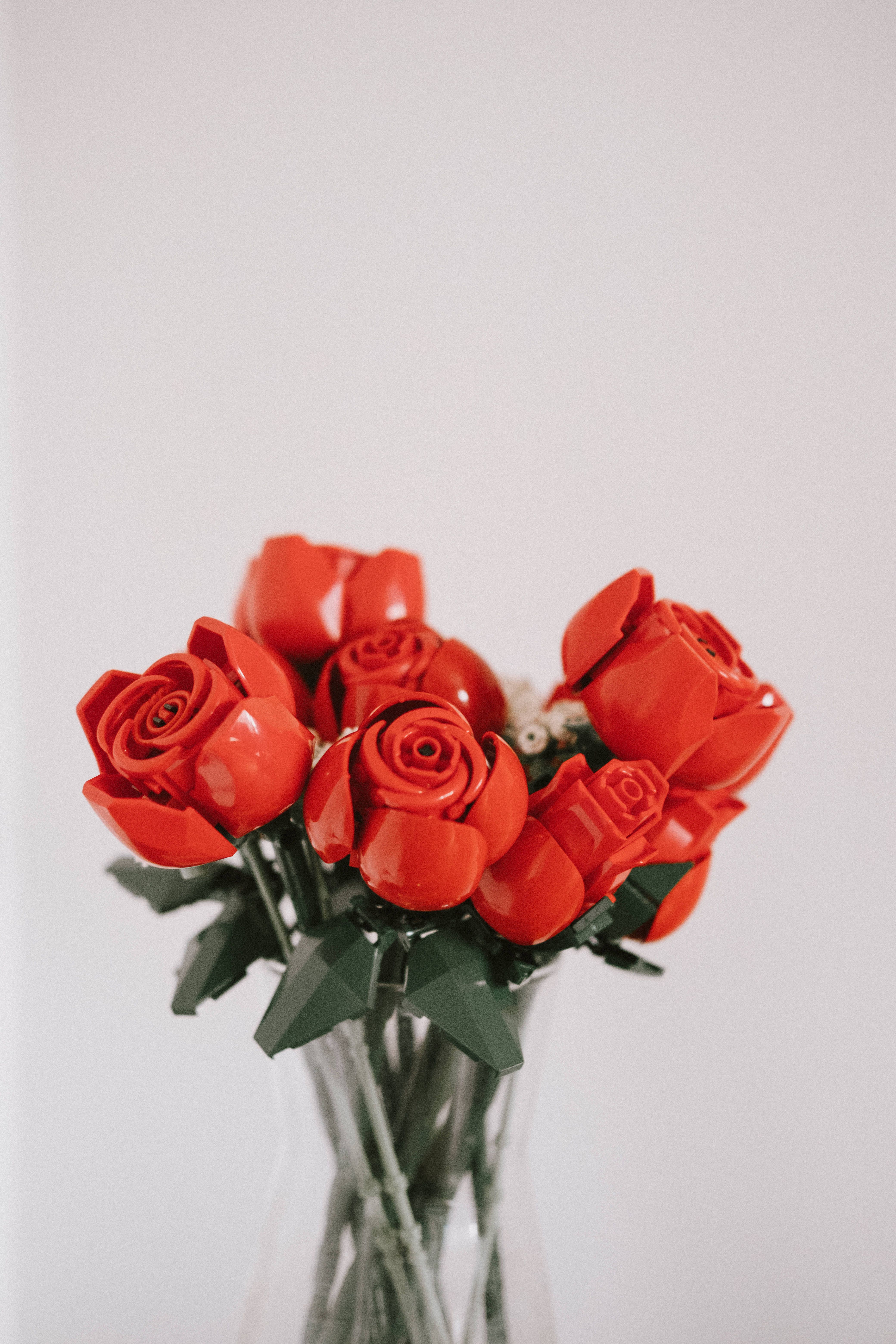 Playful and artistic arrangement of red Lego roses in a transparent vase, perfect for decor.