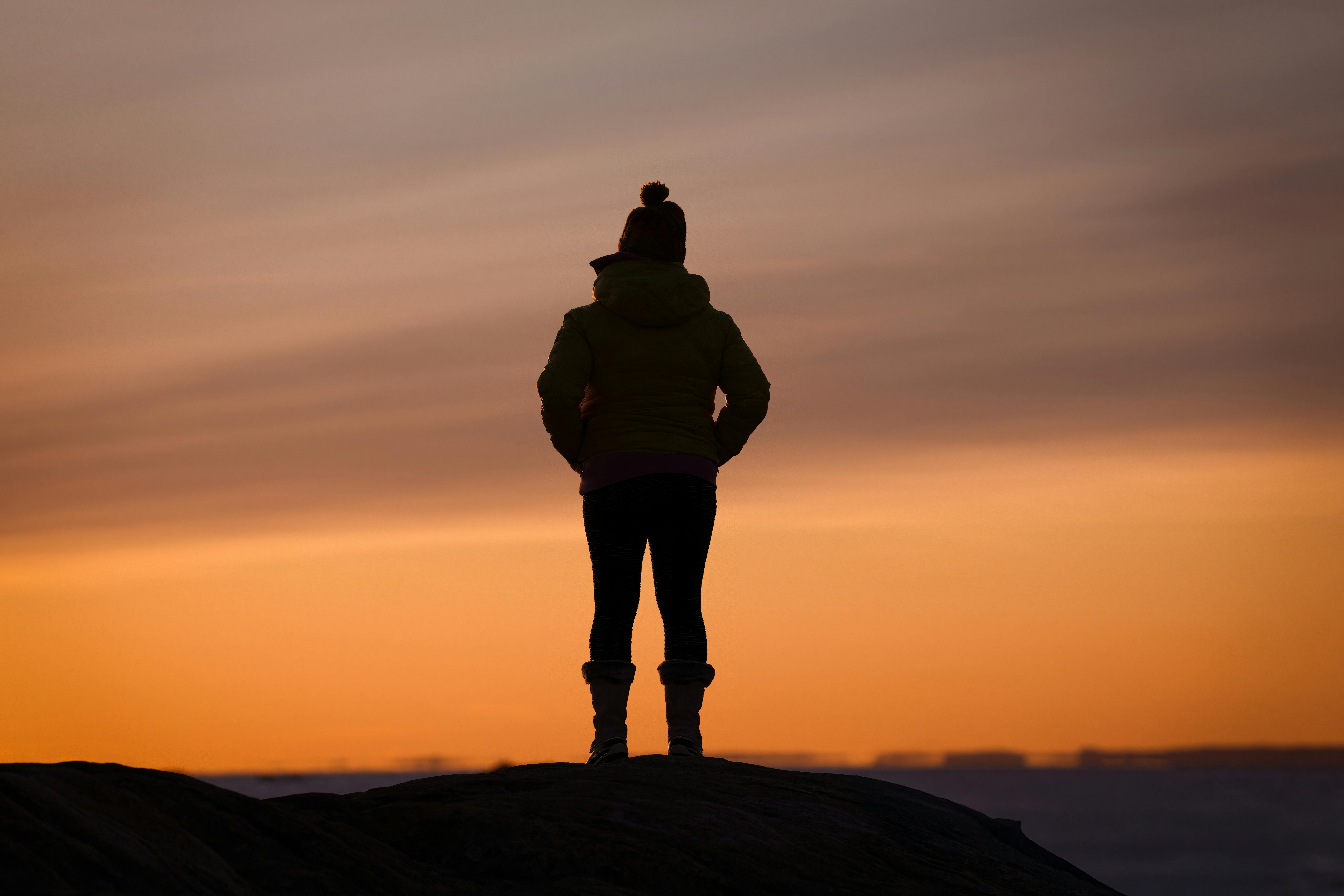 A person looking thoughtfully towards a sunrise, symbolizing reflection, hope, and new beginnings - faith based recovery