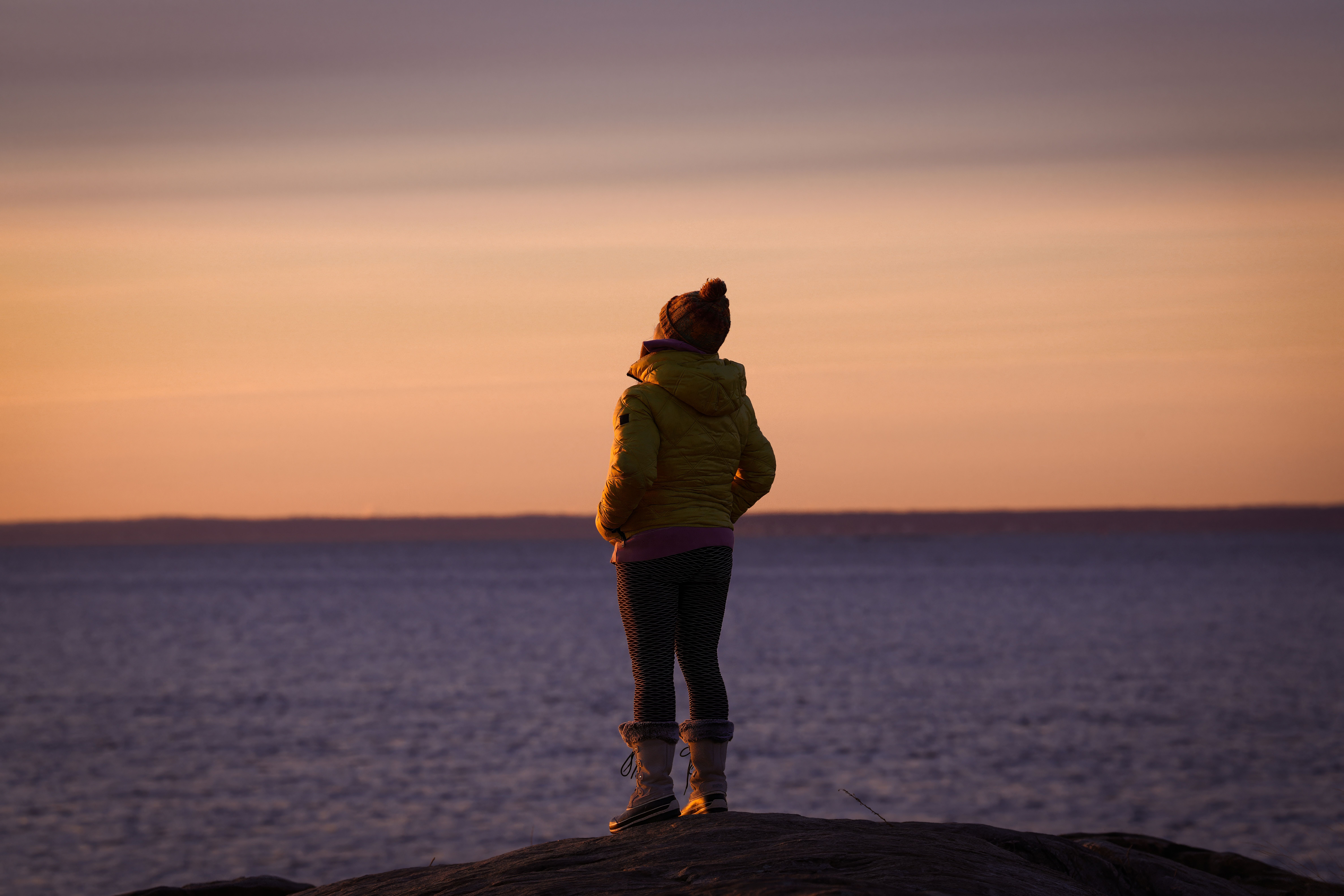 A person stands by the ocean at dawn, reflecting the peaceful winter morning in Stamford, Connecticut.