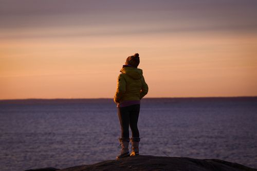 Free A person stands by the ocean at dawn, reflecting the peaceful winter morning in Stamford, Connecticut. Stock Photo
