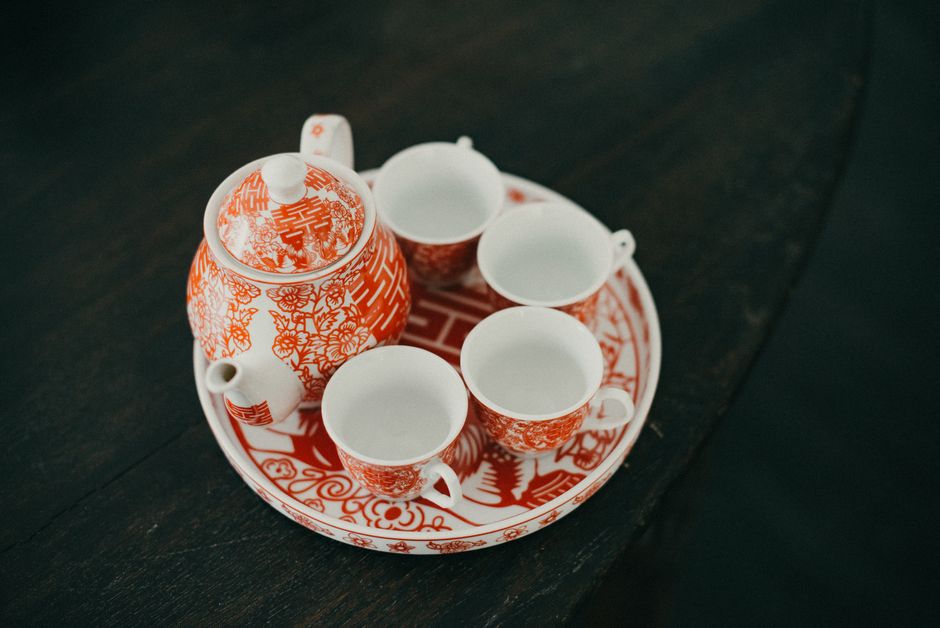 Elegant red and white Chinese teapot set on a wooden table, classic wedding decor.