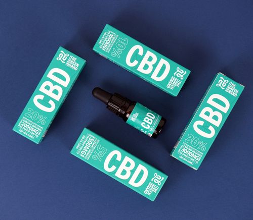 Free Flat lay of CBD oil packaging with dropper bottle against a vibrant blue background. Stock Photo